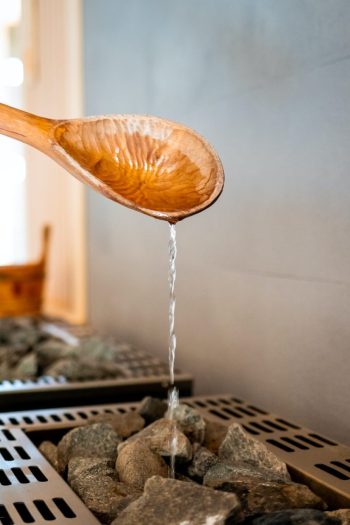 Pouring water on hot stone into heater in sauna
